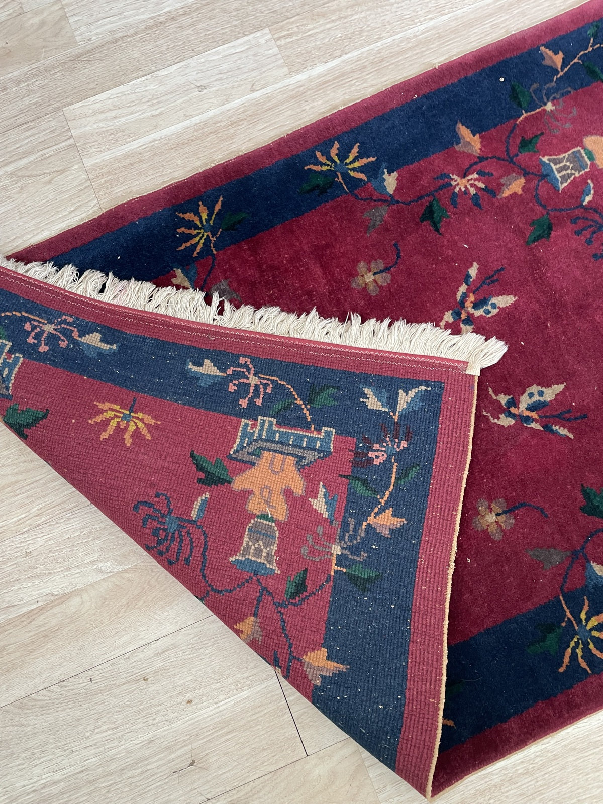 Close-up of the midnight navy border on a 1920s Chinese Art Deco rug, revealing antique scholar's bronze vessels with floral sprays, rendered with symbolic precision and painterly freedom.