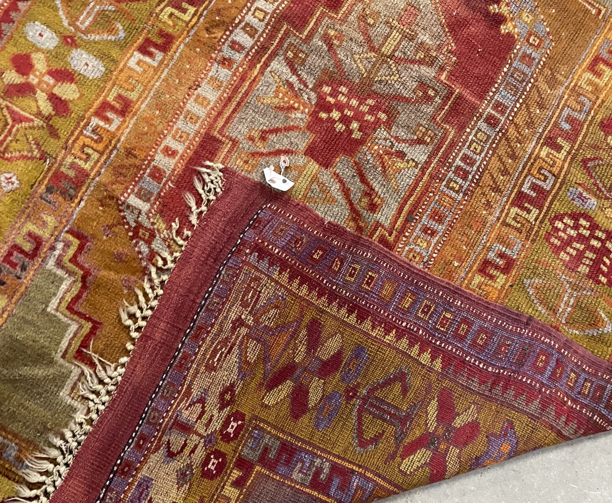 Upper end with uneven pale fringe and a burgundy flatwoven band