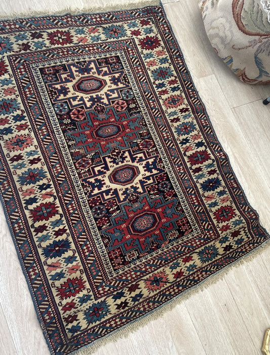Late 19th century tribal rug from Dagestan region with deep indigo field and madder red stars on floor