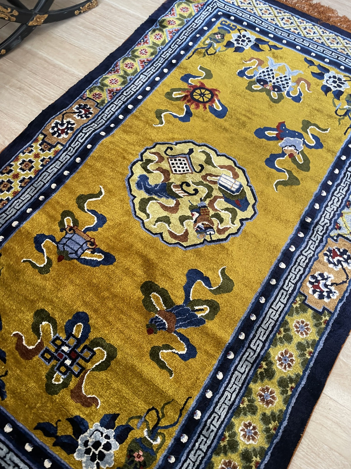 Close crop of peony pink and goldenrod floral motifs against luminous champagne field