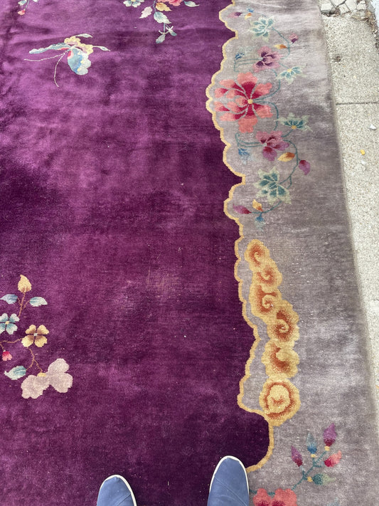 Close-up of a hand-knotted 1920s Chinese Art Deco rug showing naturalistic peonies in rose, coral, and gold, plus a small kingfisher bird among the blossoms.