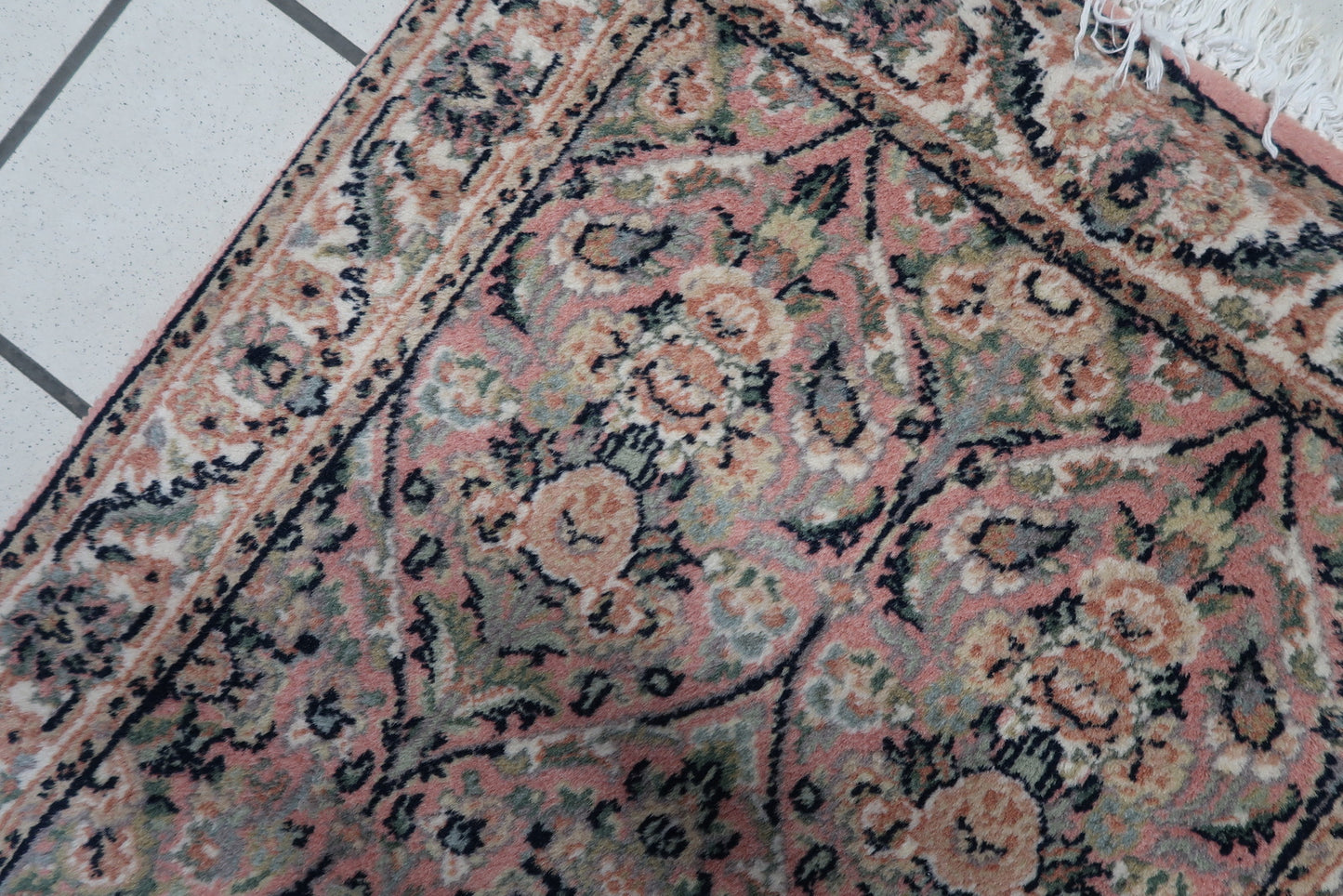 Close-up of the turquoise background and intricate motifs on the vintage Persian Kerman rug.