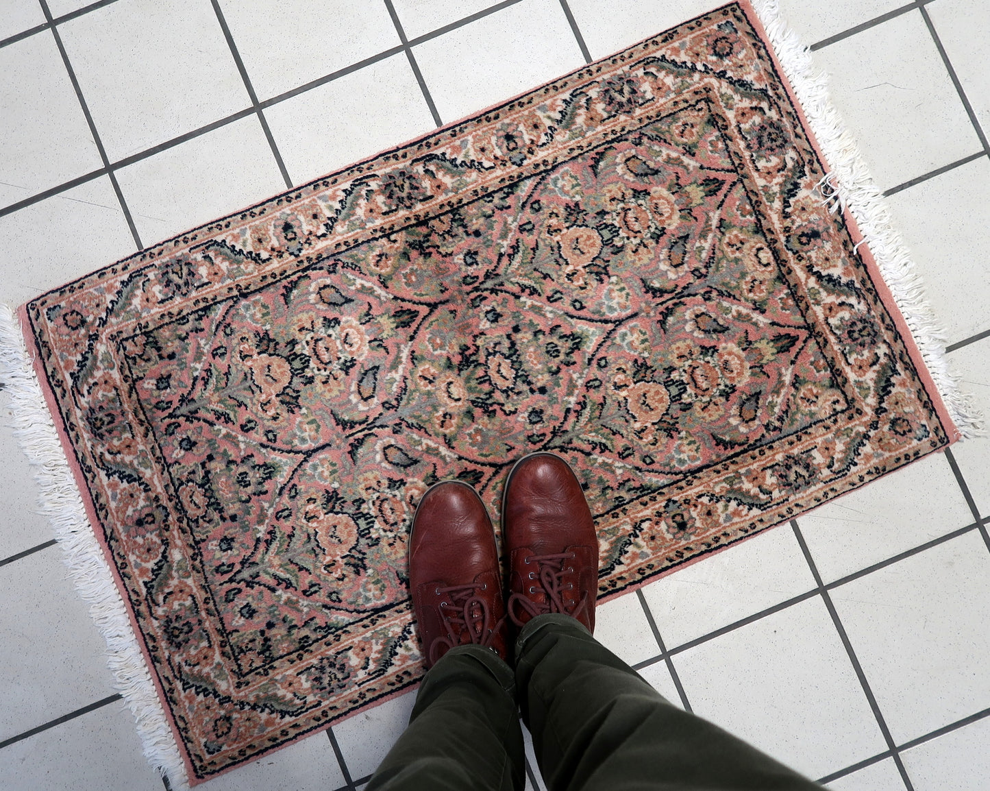 Close-up of the pastel pink floral motifs on the vintage Persian Kerman rug.