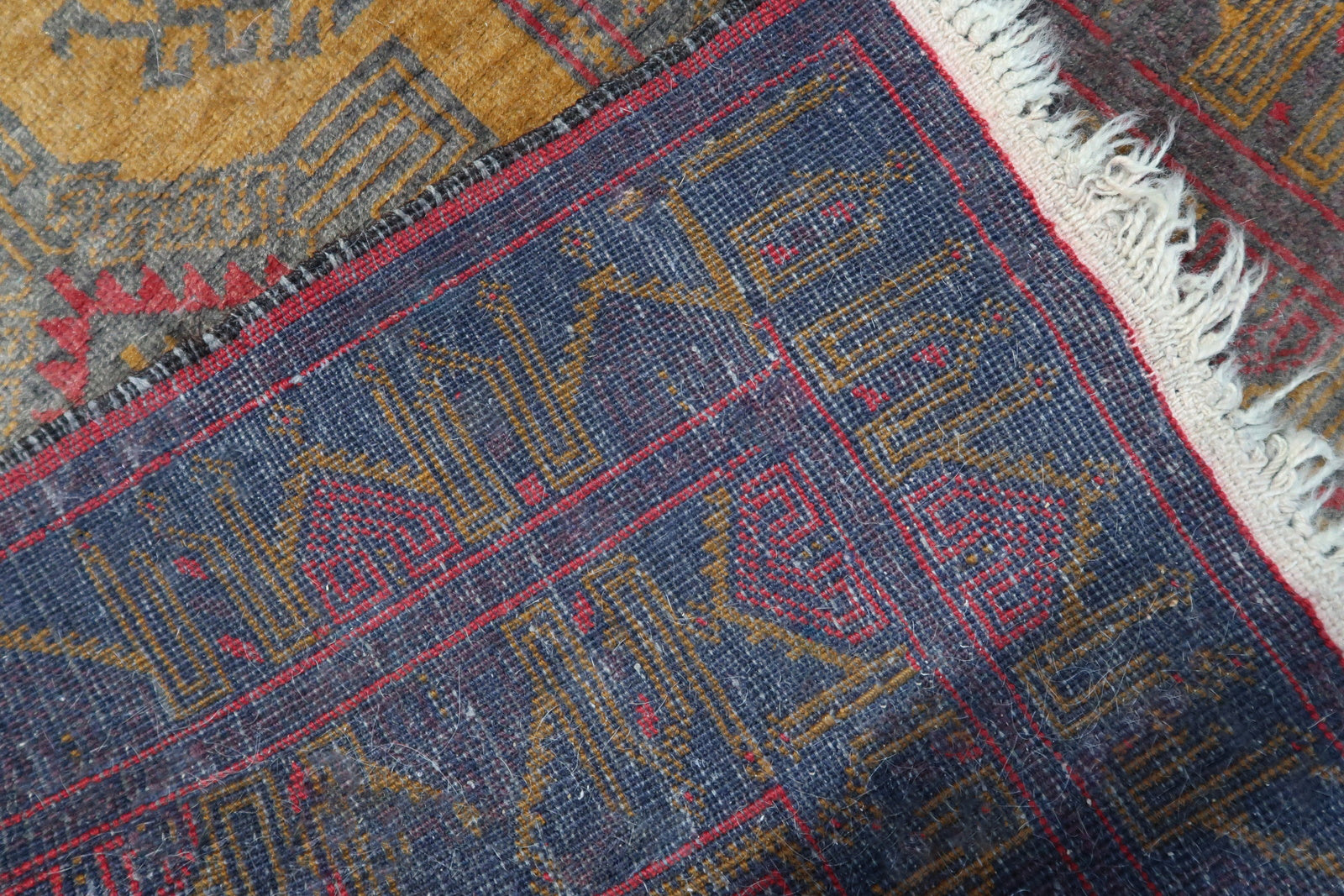 Back side of the handmade vintage Afghan Baluch rug revealing the woven structure and natural wool material