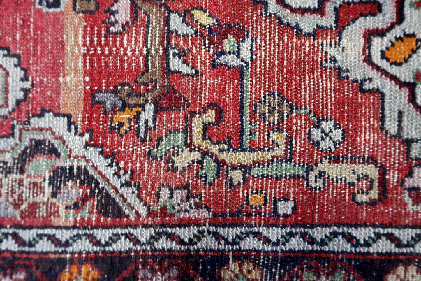 Close-up of an intricately designed rug with red, white, and black patterns.