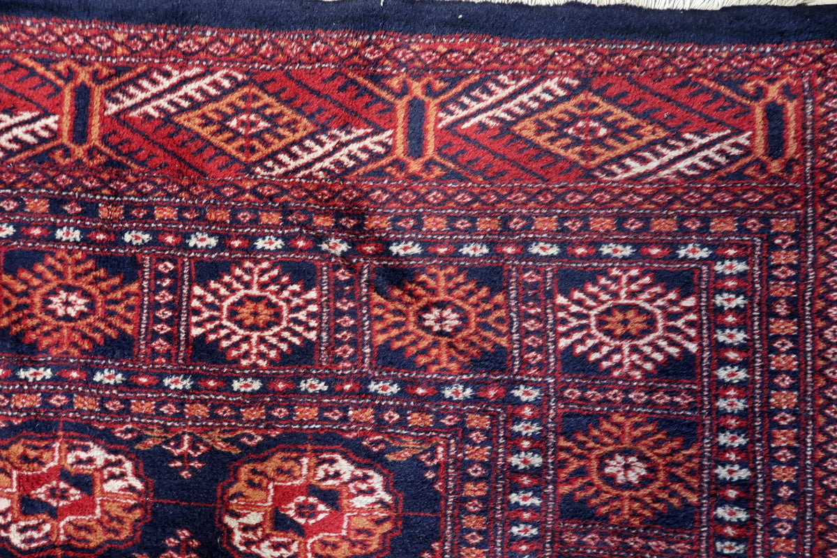 A side angle of the rug’s deep red and navy color palette