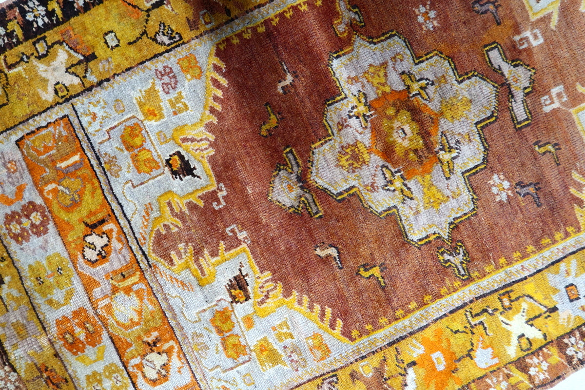 Soft, earthy tones of rust, beige, and ochre in the antique tribal rug
