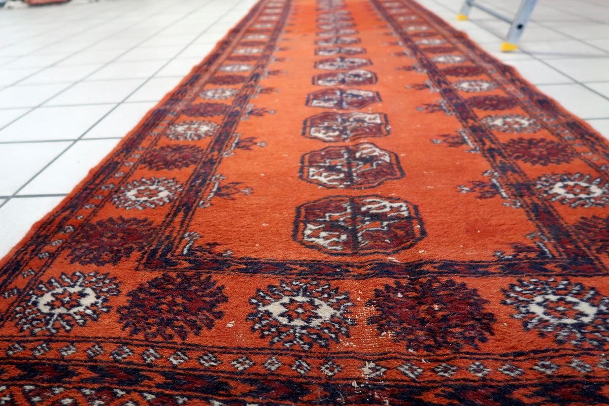 Subtle wear on the edges of the Bukhara carpet, adding to its vintage charm