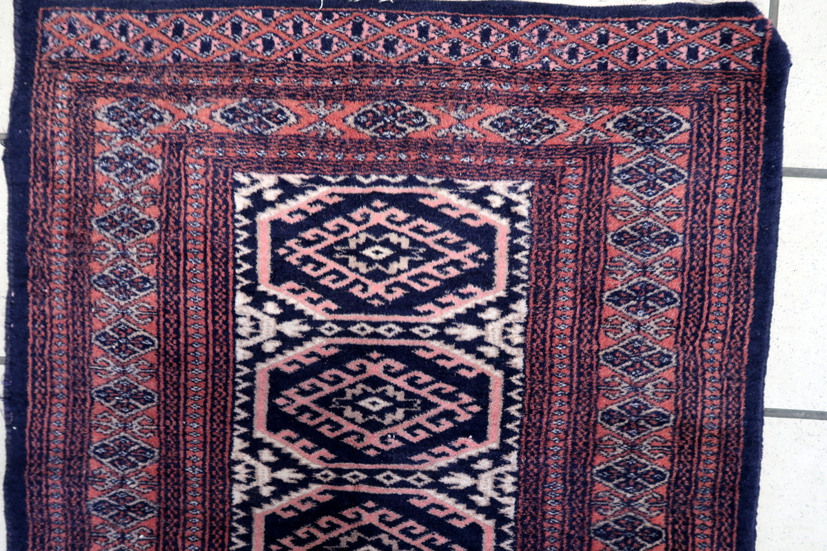 Close-up of the intricate navy blue and red patterns on the small Bukhara rug