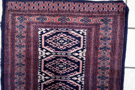 Close-up of the intricate navy blue and red patterns on the small Bukhara rug