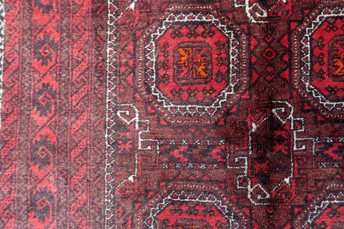 A vintage Afghan Baluch rug rolled up, showcasing its size and condition