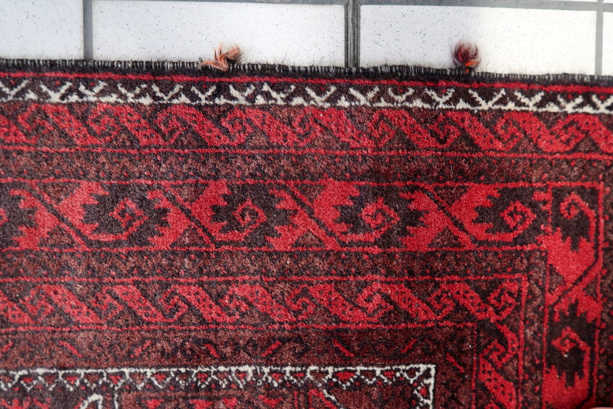 Rug spread out on a wooden floor, emphasizing its aged character