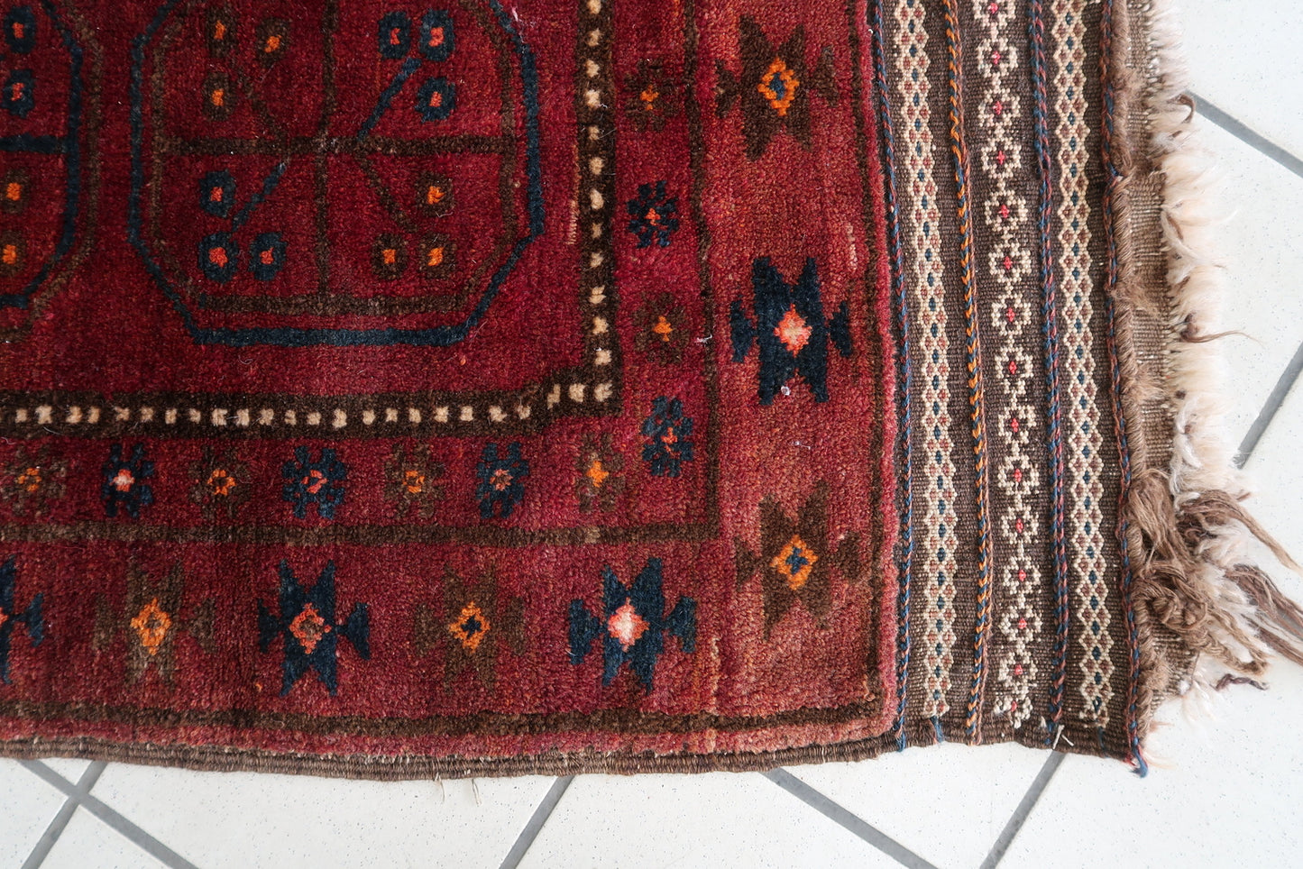Rich red and dark blue color palette on an antique Afghan wool rug