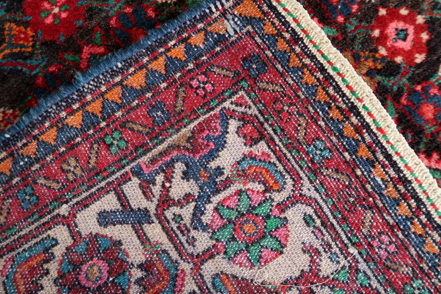 Detailed view of floral and vine patterns on vintage Persian rug