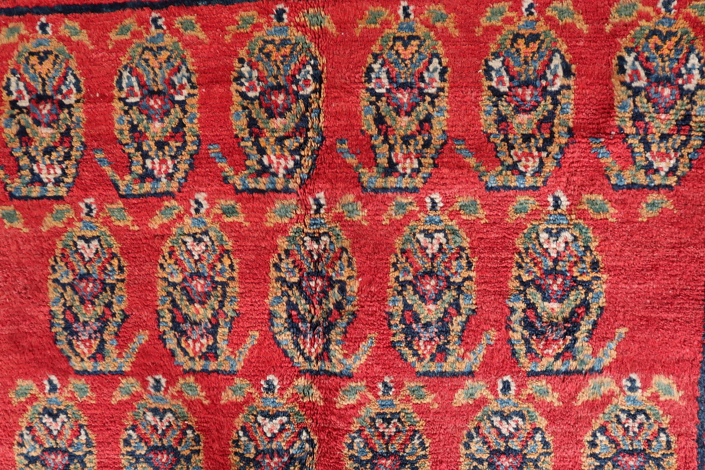 Angle shot capturing the rich, saturated red background color of the vintage rug.