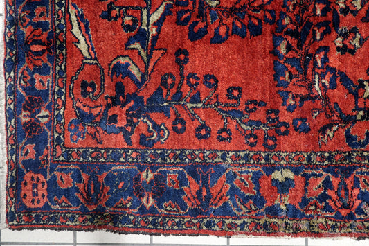 Early 20th century Persian village carpet with a rich madder-red field and symmetrical arrangement of blossoming branches in navy, teal, and gold. 5'8" x 6'7".