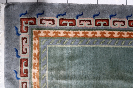 Close-up of singular abstract Shou or endless knot-inspired motif on a vintage Tibetan wool carpet with soft luster
