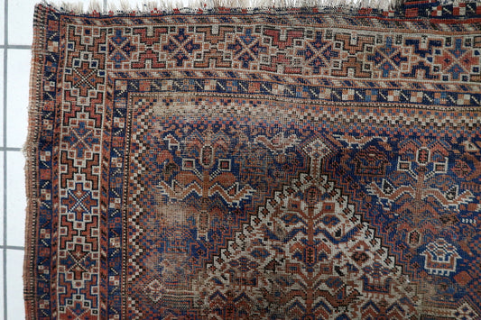 Close-up of intricate small-scale tribal motifs and geometric patterns on a hand-knotted Persian Khamseh carpet