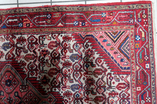 Vintage red and navy blue Persian Hamadan carpet with central diamond medallion laid on floor