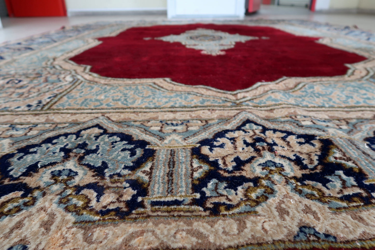 Close-up of the wide ivory/pale blue inner sub-border on a vintage Persian Kerman rug, showing a continuous light floral scroll in sky blue, pale pink, and gold – airy, elegant, and characteristic of fine Kerman production.