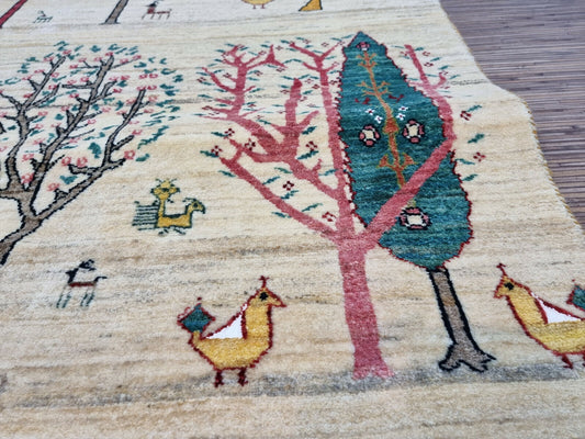 Close-up of the tree with green leaves and red trunk on the Persian Gabbeh rug