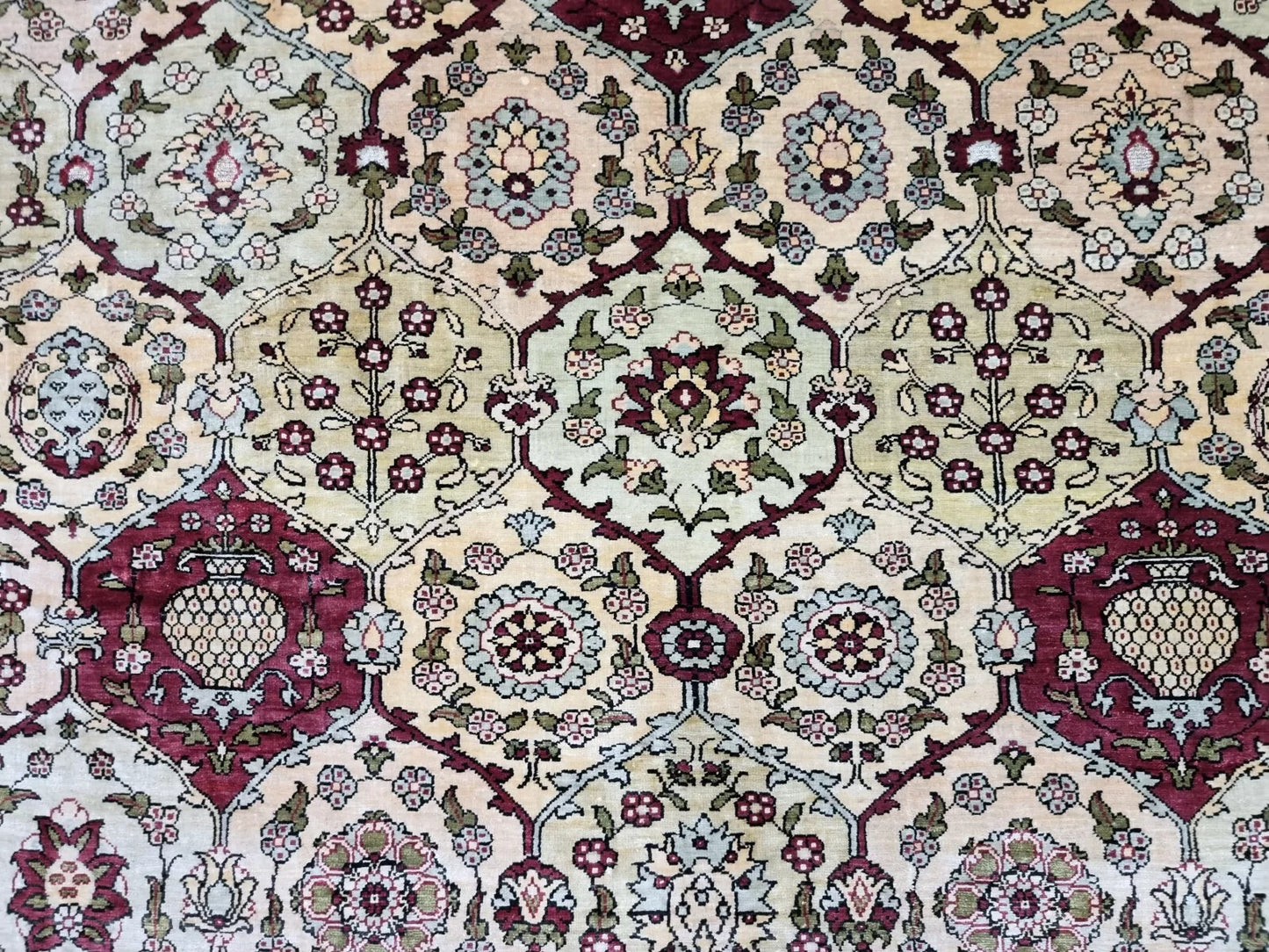 Vibrant burgundy and turquoise accents on a hand-knotted silk Hereke rug