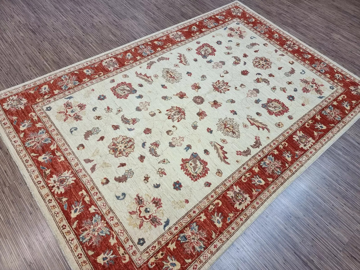 Decorative rug with red and beige pattern on a wooden floor