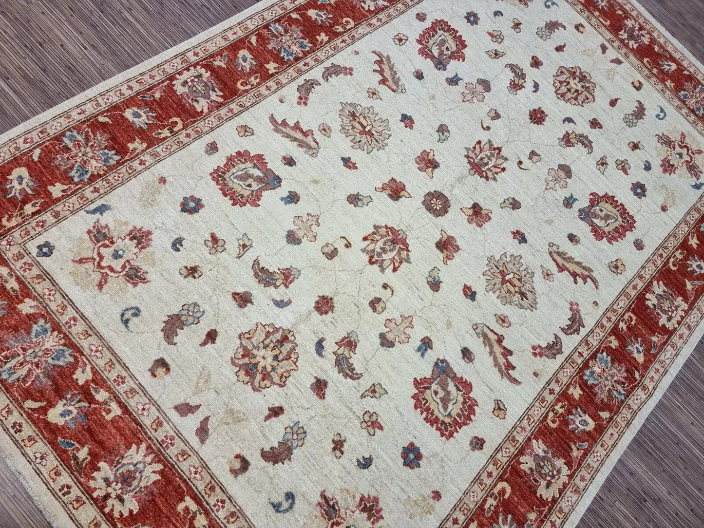 Decorative rug with red and beige floral pattern on a plain background
