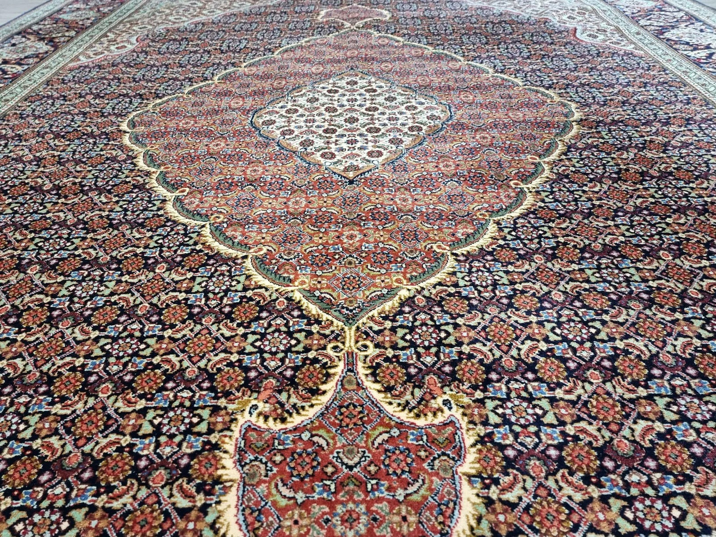 Full view of a vintage Persian Tabriz rug laid flat, showing its rectangular shape, multiple borders, and classic floral medallion design in rich blue tones.