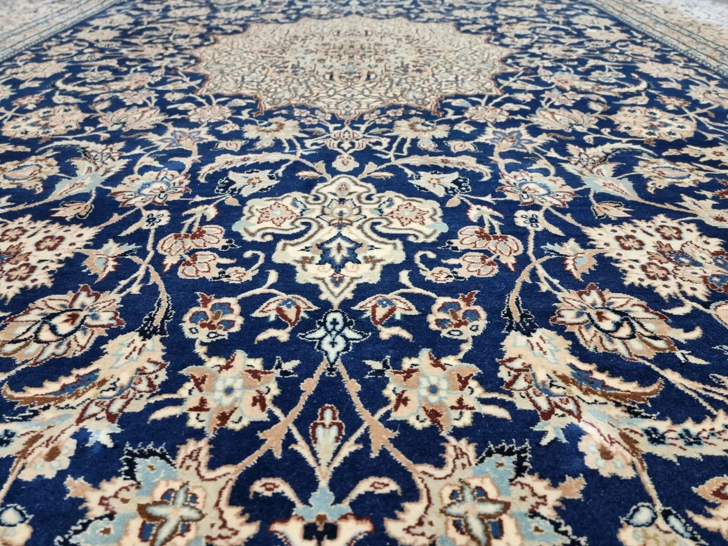 Detail of the border on a 1920s Persian Nain carpet, revealing repeated floral and vine motifs in navy and ivory with fine silk accents for added luster.