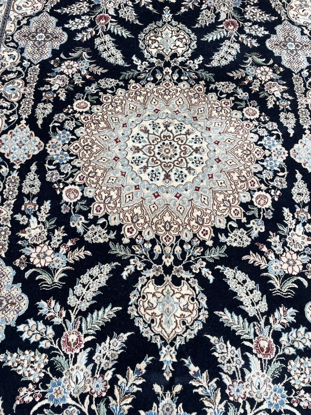 Navy blue and ivory vintage Persian rug with soft pale blue and burgundy floral highlights, made of wool.