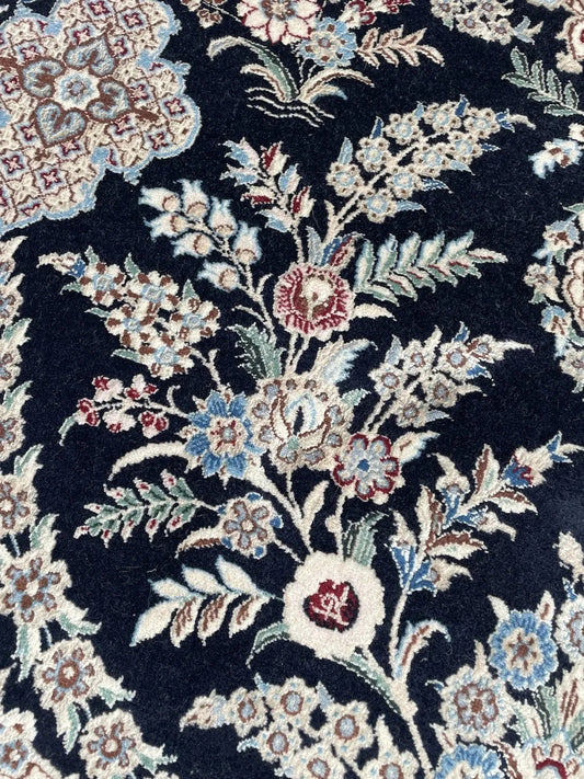 Deep navy vintage Persian rug with central ivory medallion, arabesques, and soft blue and burgundy floral motifs.