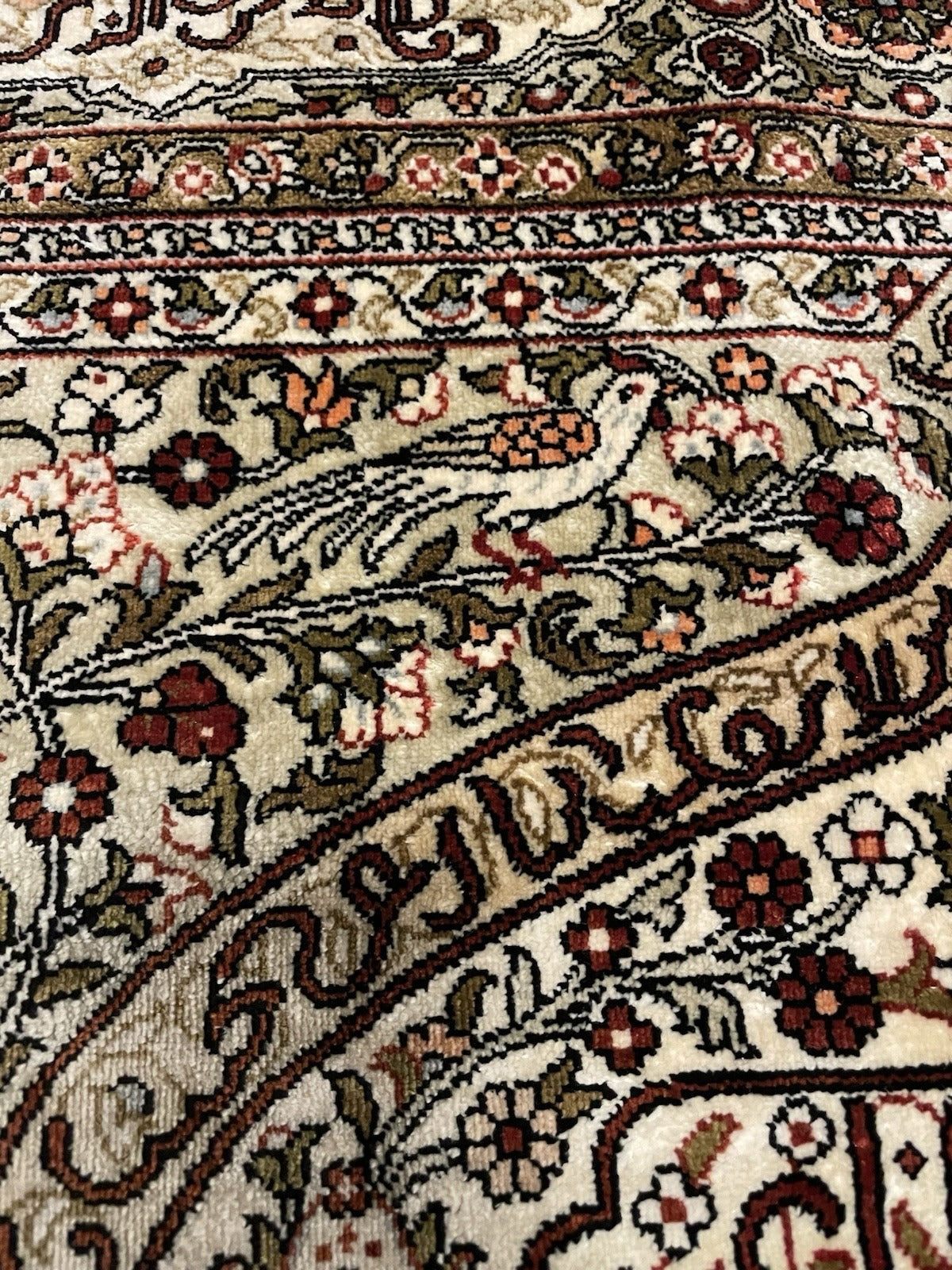 Full view of a 1970s Hereke silk prayer rug with a paradise bird composition and Arabic calligraphy, featuring a pointed mihrab arch framing the ivory prayer field.