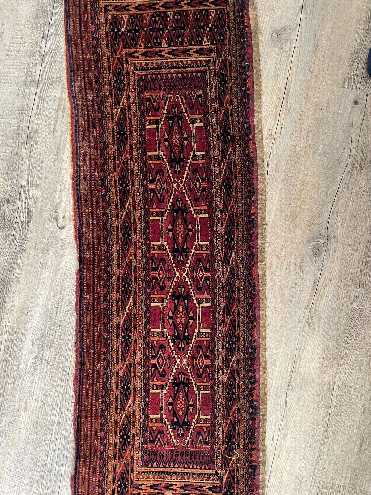 Side view of the antique Yomud rug showing rich red tones and symmetrical motifs