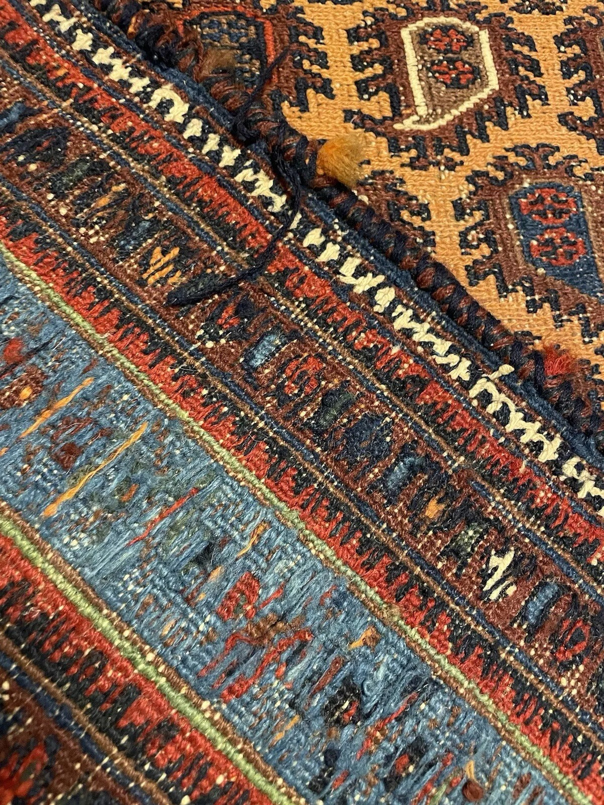 Detailed corner view of antique Afghan Sumak rug with tassel accents