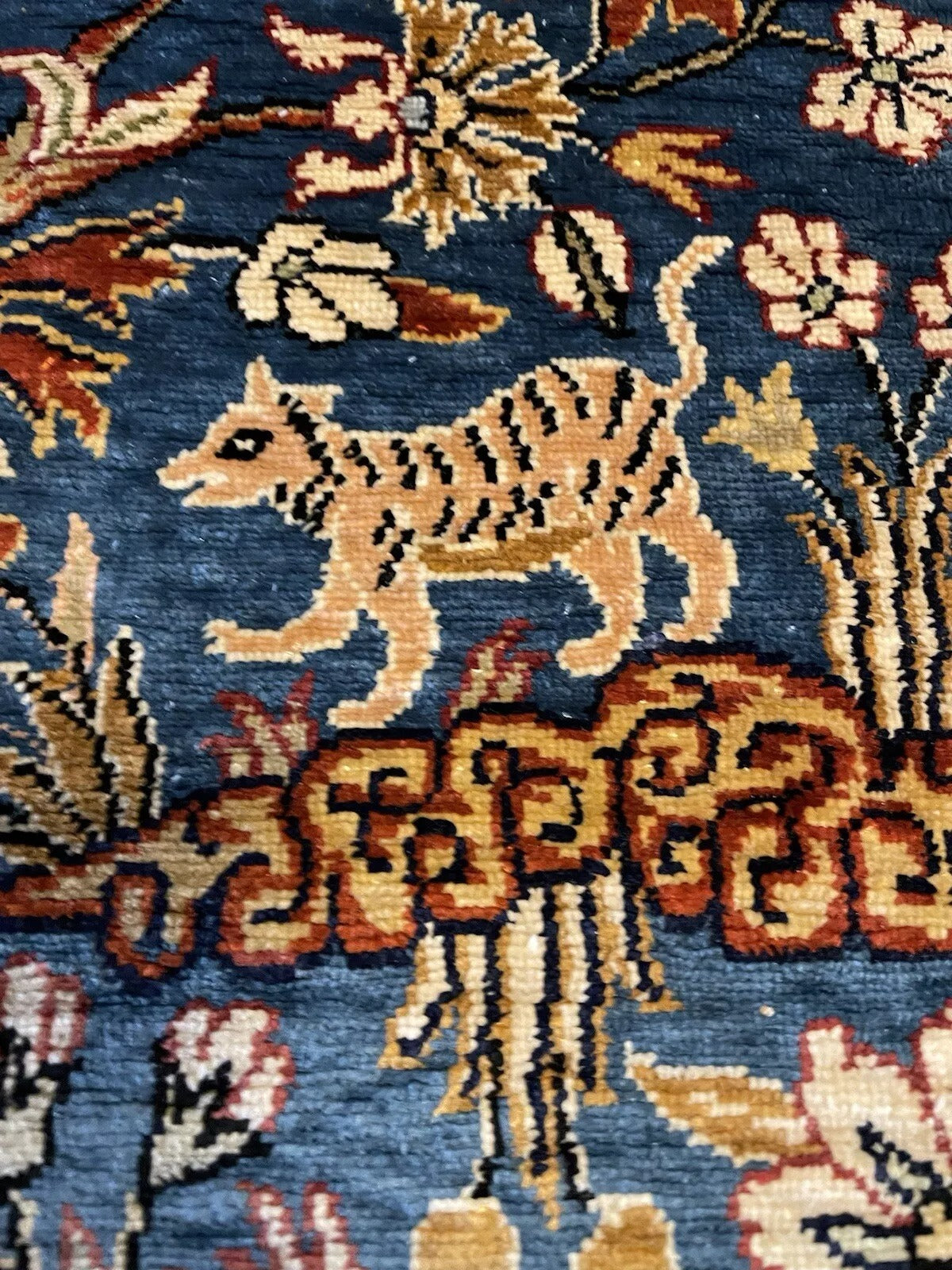 Dark blue silk rug featuring birds, deer, and rabbits.