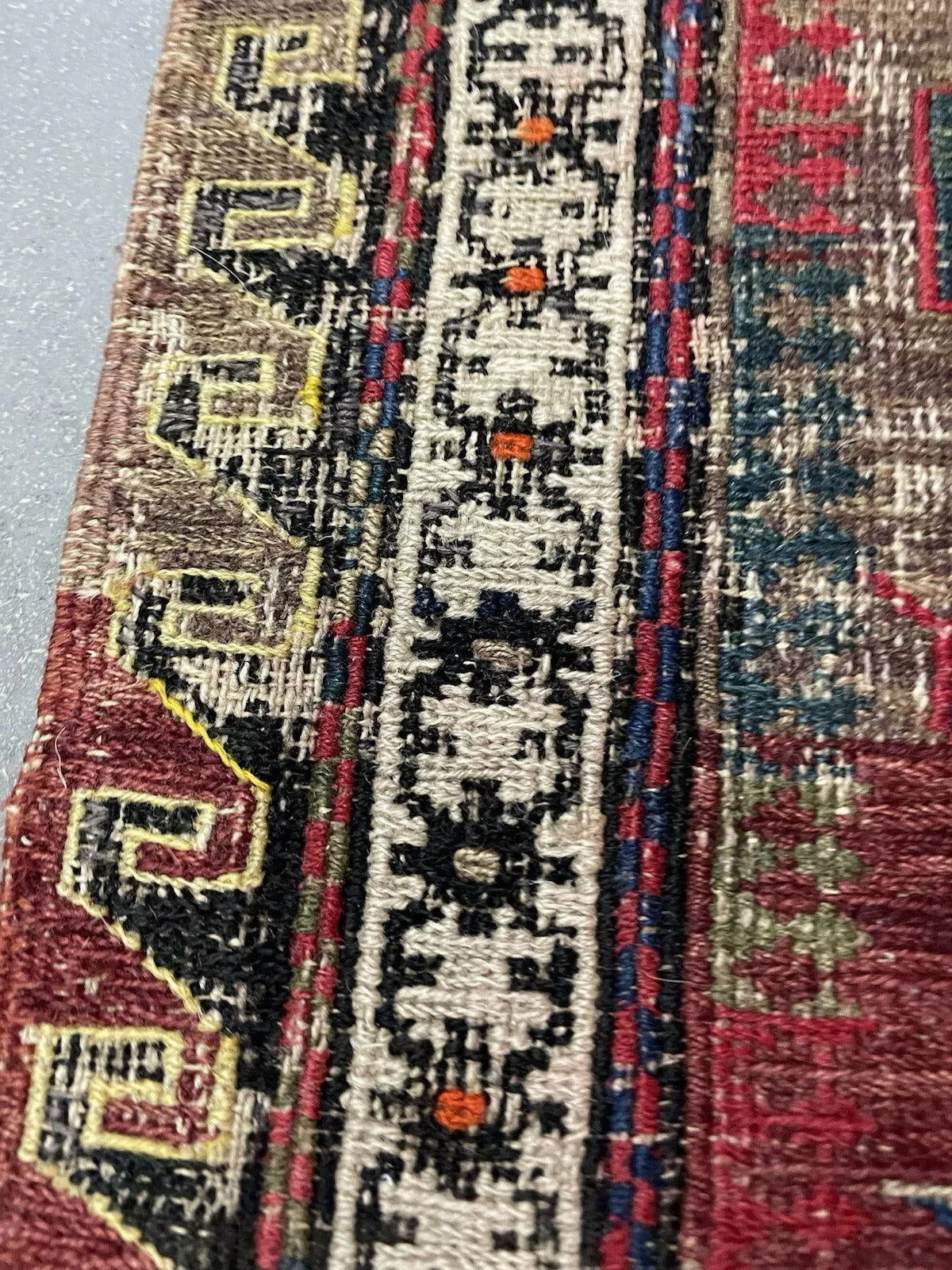 Detail of faded pattern bands across rug field