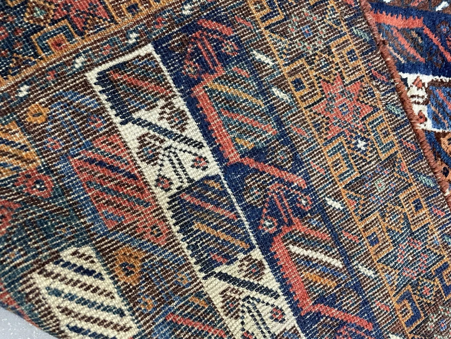 Texture shot showing the dense, durable wool pile of the nomadic Baluch carpet.