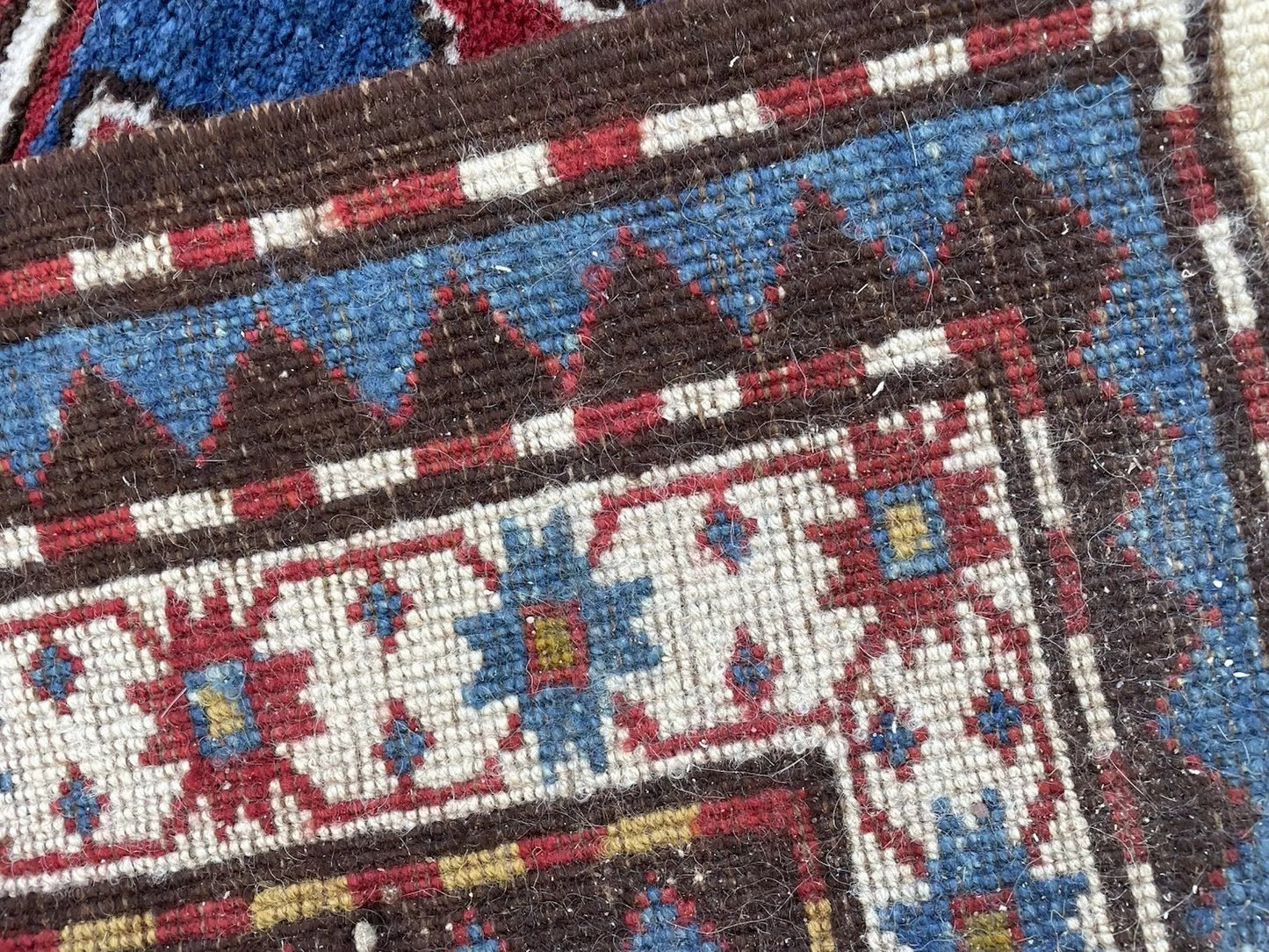 Detail of the rug's fringe and selvedge, showcasing its original antique condition.