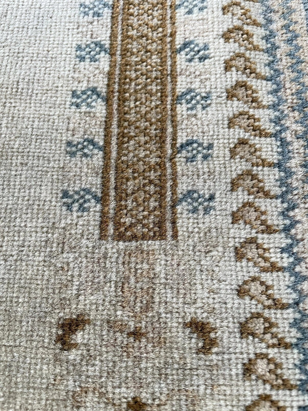 Texture shot showing the soft, aged wool pile of the Ghurdes carpet.
