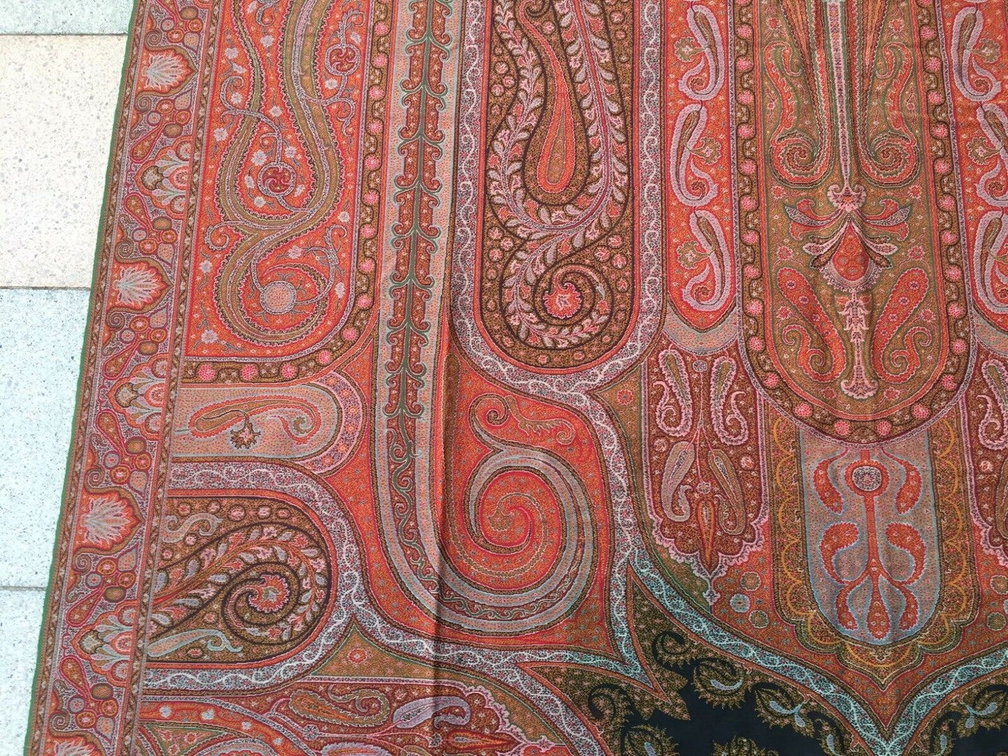 Artistic display of the shawl as a statement piece on a clothing rack, showcasing its vibrant colors and intricate patterns