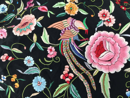 Close-up of the intricate silk embroideries depicting delicate flowers in shades of pink, white, and other colors against the black canvas