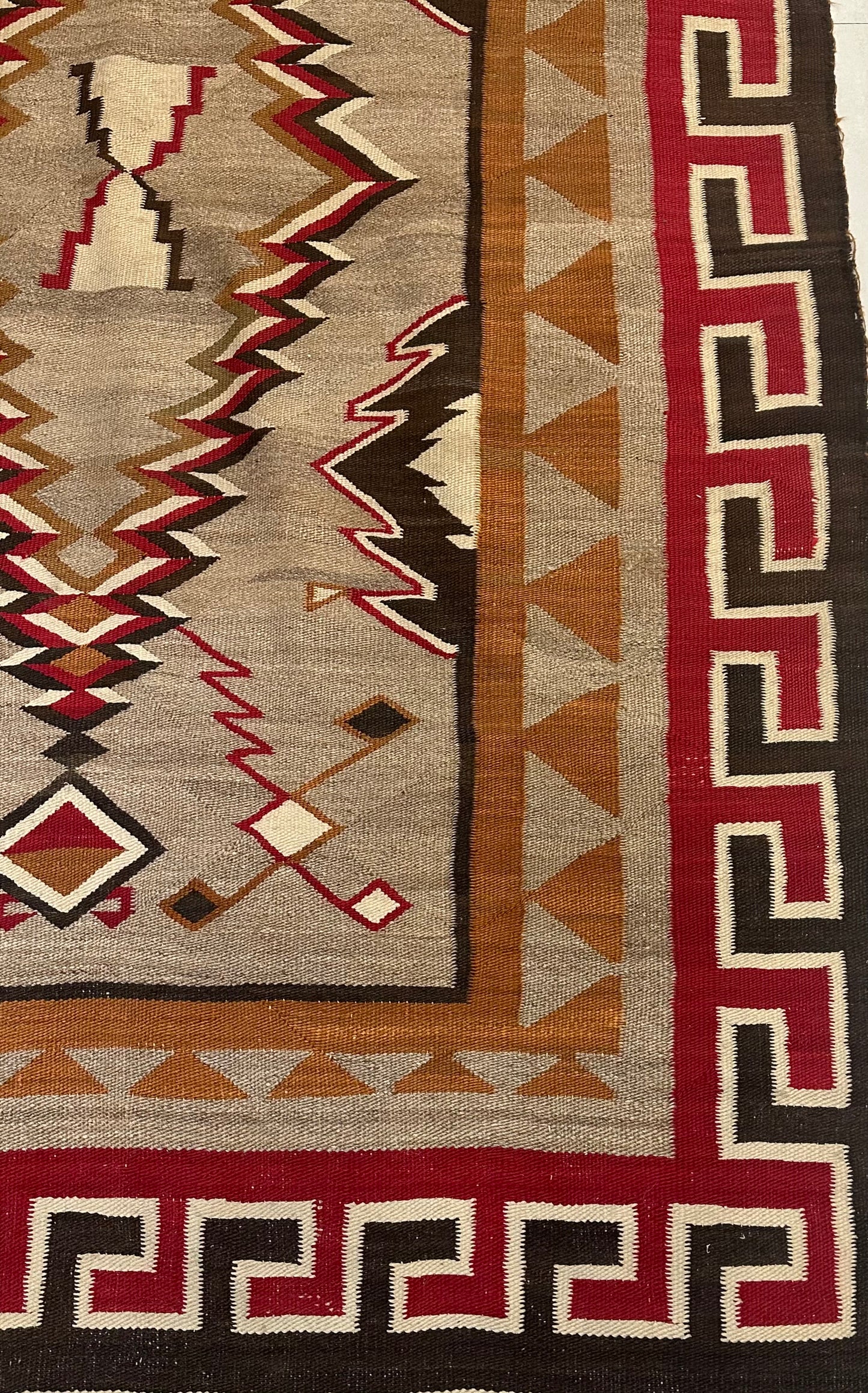 Vintage Native American Navajo rug with earthy brown, beige, and red tones.