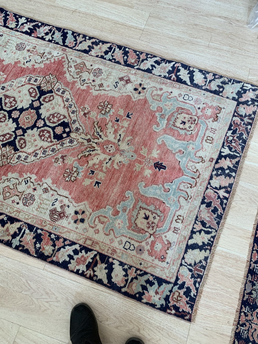 The central medallion of the antique Turkish rug in soft antique rose and navy blue.