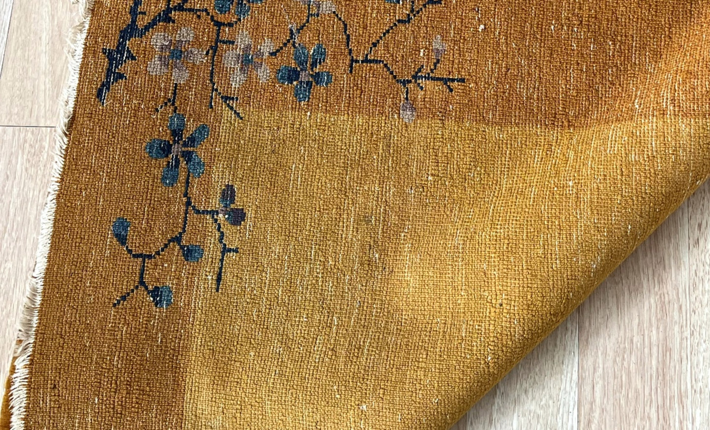 Close-up of delicate blue and pink floral details on the vintage rug