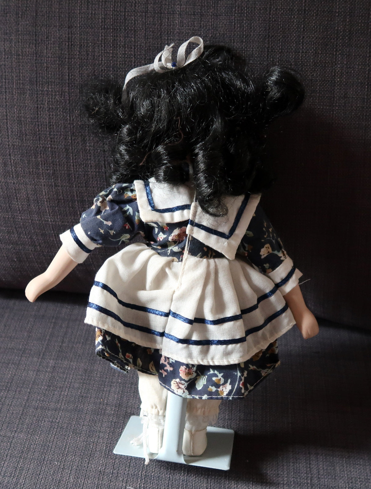 Classic vintage porcelain doll with a metal display stand