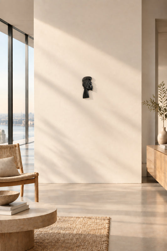 Fine carving details on the smooth brow, delicate nose line, and refined lips of an ebonized tropical hardwood profile portrait.