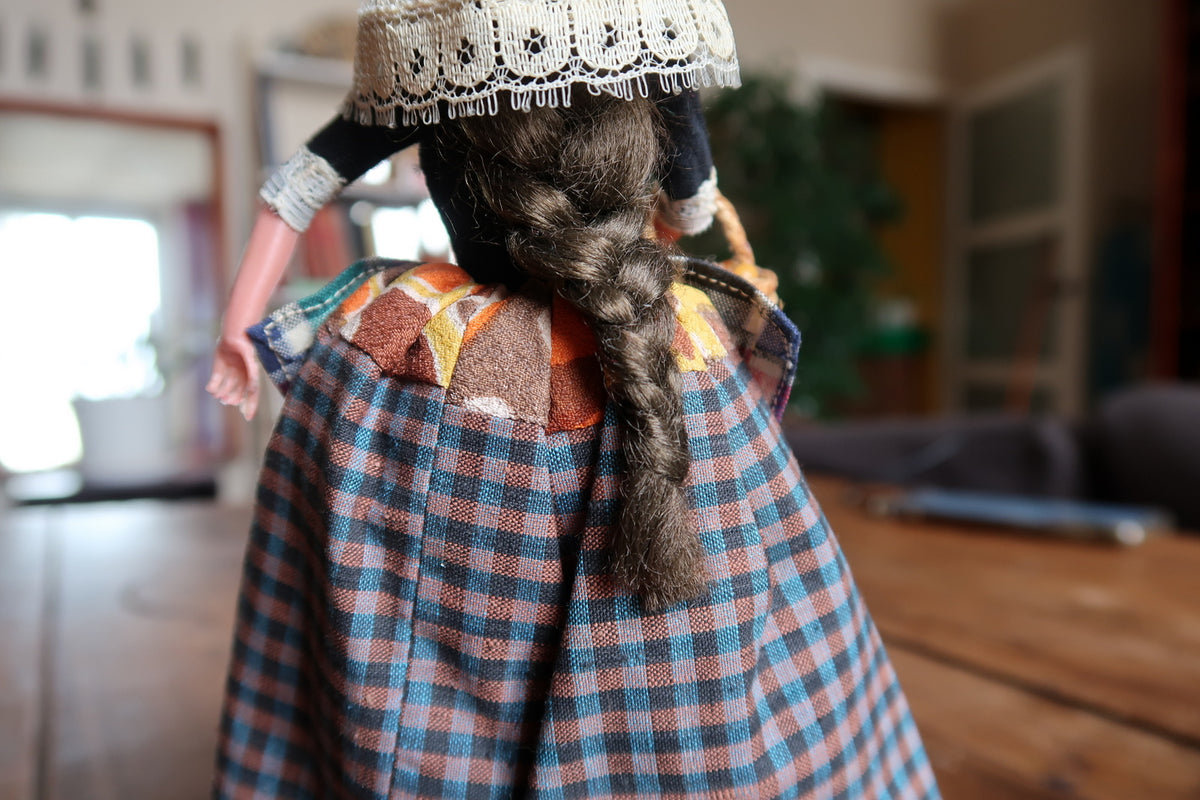 Close-up of long brown braid over checked fabric