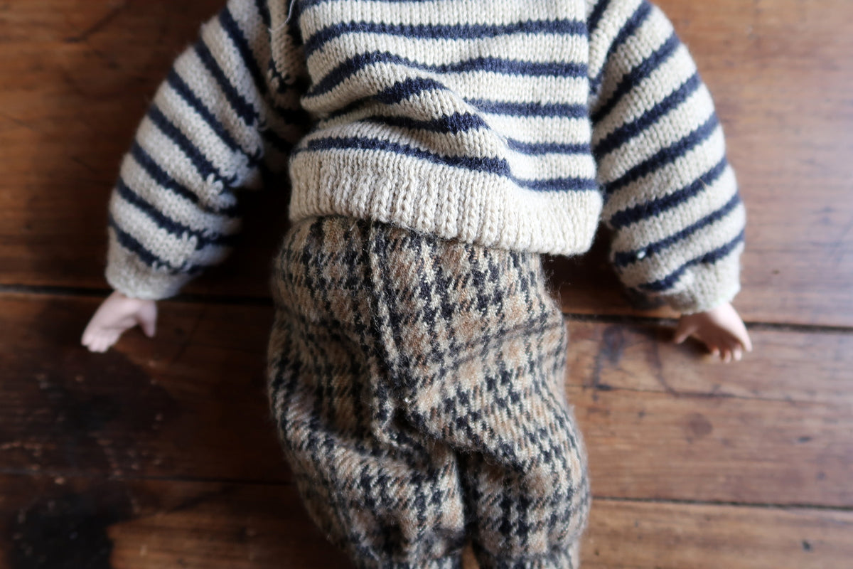Full front view of the porcelain boy doll with tousled hair and country-inspired clothing.