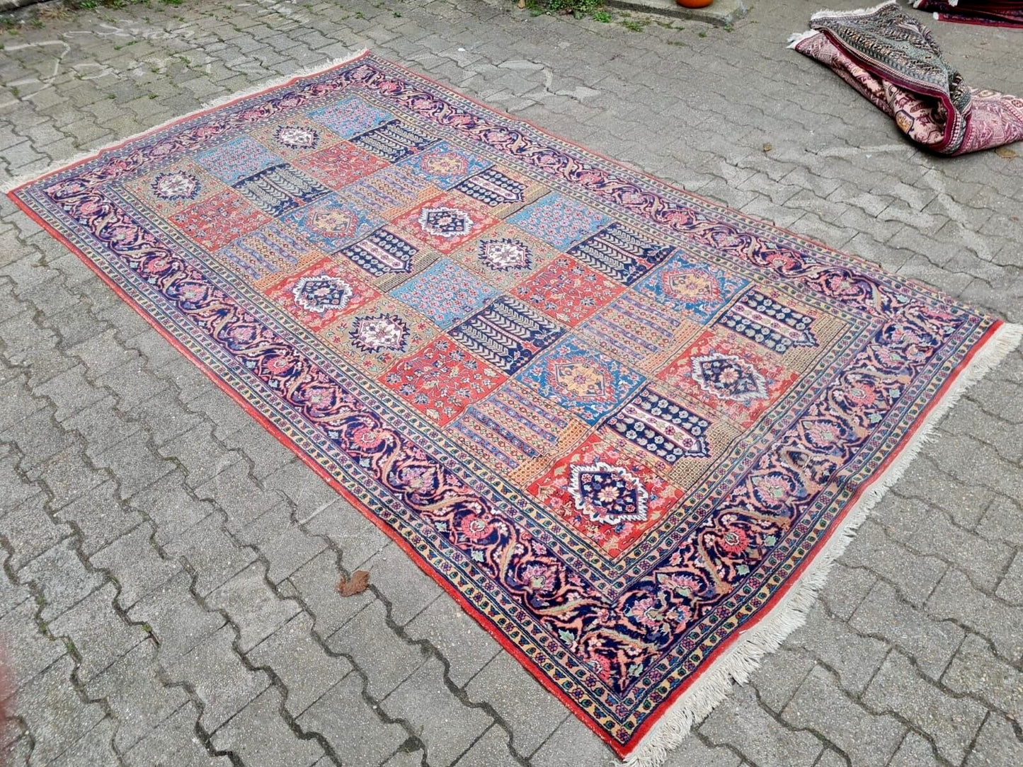 Persian rug showing localized low pile areas consistent with age.